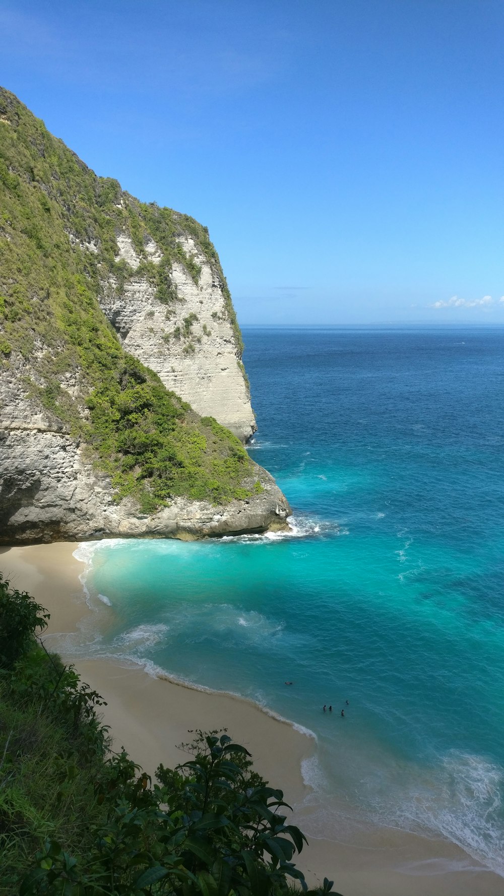 green and gray rock formation beside blue sea under blue sky during daytime