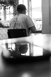 A candid moment of a person adjusting their Lumina Apparel cap while waiting at a city café.
