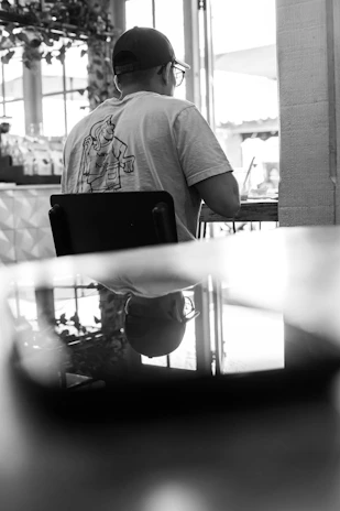 A candid moment of a person adjusting their Lumina Apparel cap while waiting at a city café.