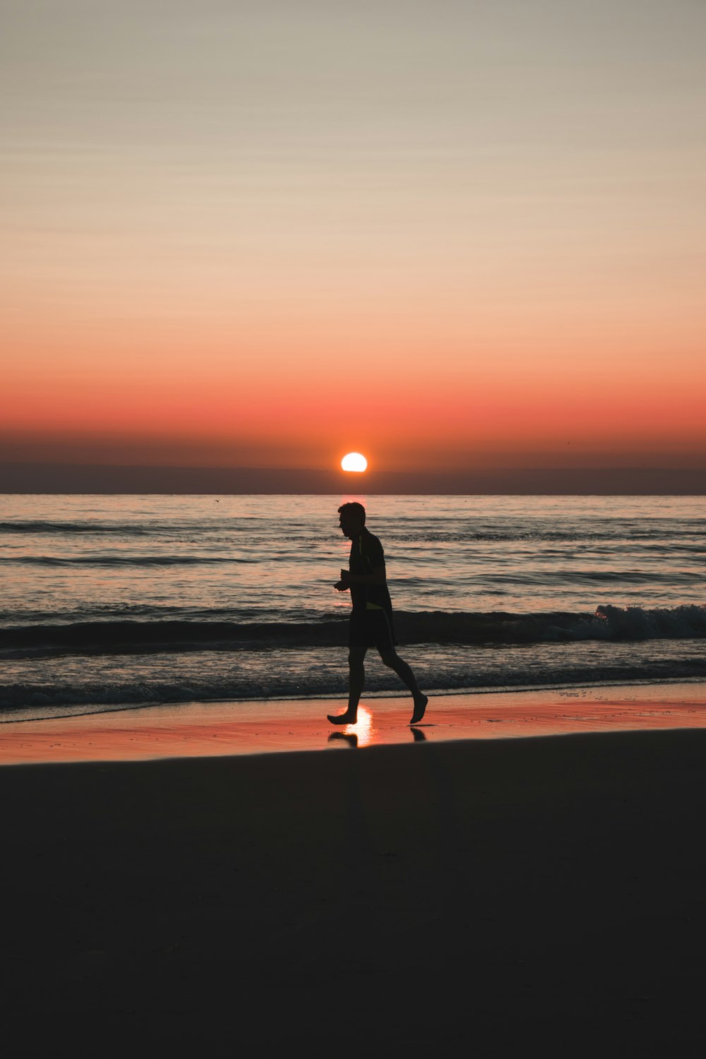 silhouette of woman walking on beach during sunset