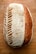 A beautifully crafted loaf of sourdough bread with intricate scoring patterns on the crust, lying on a wooden surface. The bread has a crackling texture with a blend of light and dark brown hues, indicating a well-baked exterior.