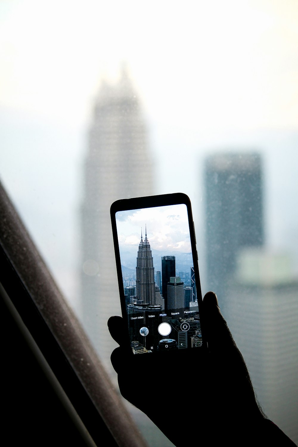 person taking photo of city buildings during daytime