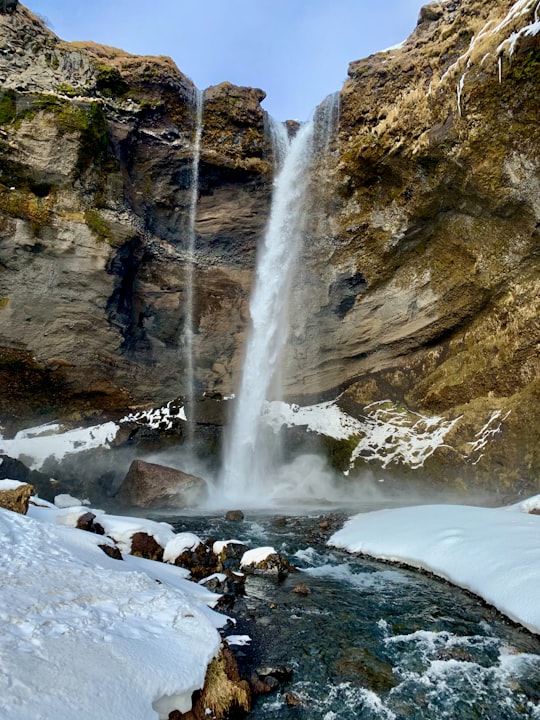 water falls on rocky mountain during daytime in Kvernufoss waterfall Iceland