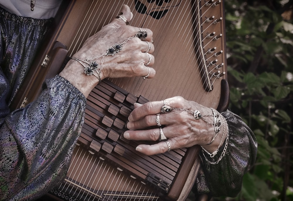 Persona con camisa gris de manga larga tocando un instrumento de cuerda