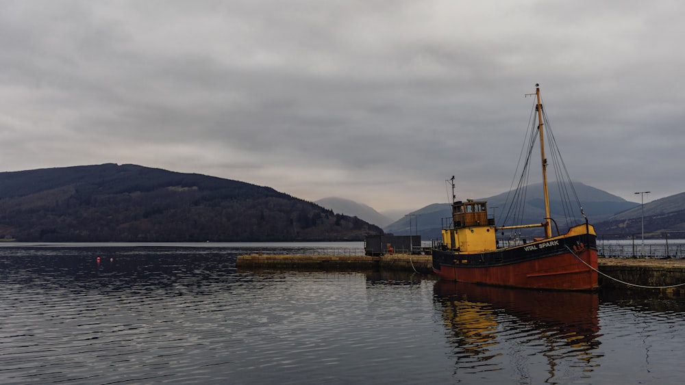 brown boat on water near mountain during daytime