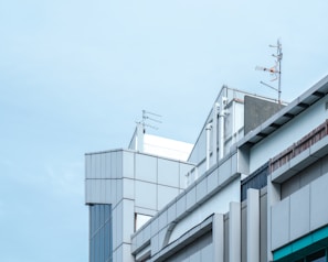 A geometric architectural structure with modern design elements featuring metal panels and glass. Several antennas are mounted on the rooftops, suggesting a focus on communication technology.