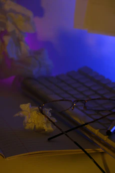 A calm desk scene with glasses resting on top of a journal beside a sleek pen.