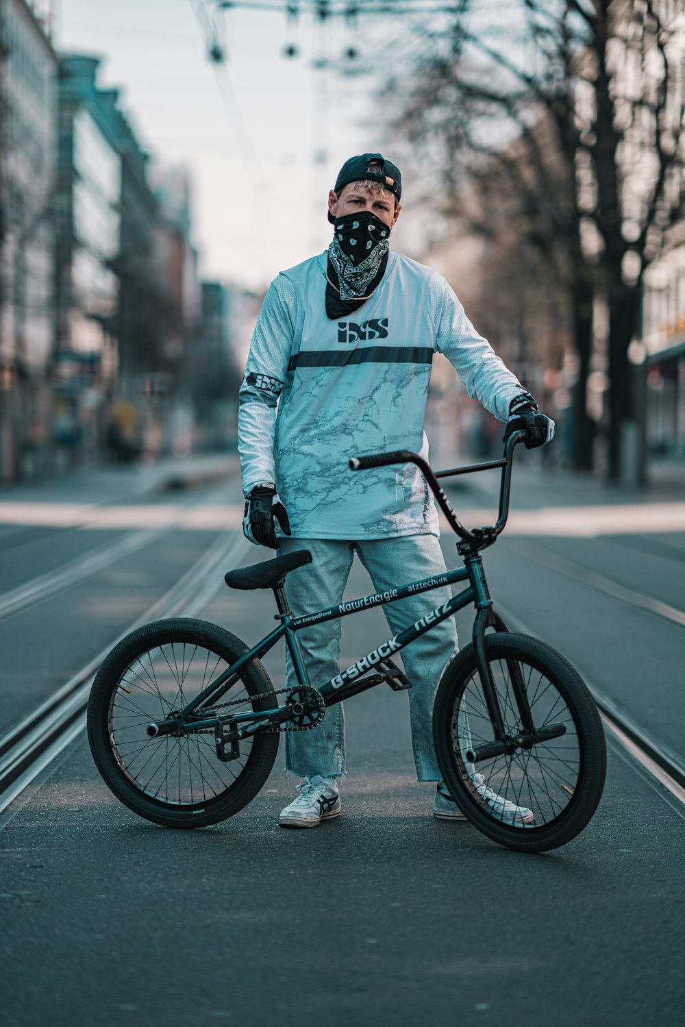 man in white long sleeve shirt riding on black bicycle on road during daytime