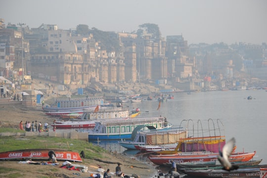 red and green boat on body of water near city buildings during daytime in Varanasi India