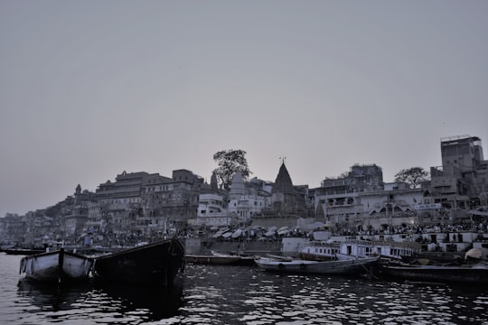 black boat on body of water near city buildings during daytime in Dashashwamedh Ghat India
