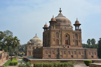 A scenic view of a famous Indian monument surrounded by lush greenery and clear blue skies.
