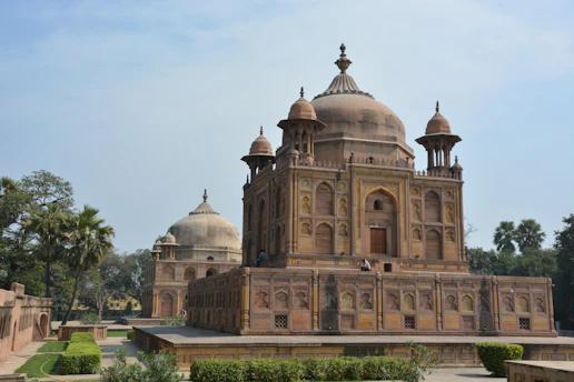A scenic view of a famous Indian monument surrounded by lush greenery and clear blue skies.