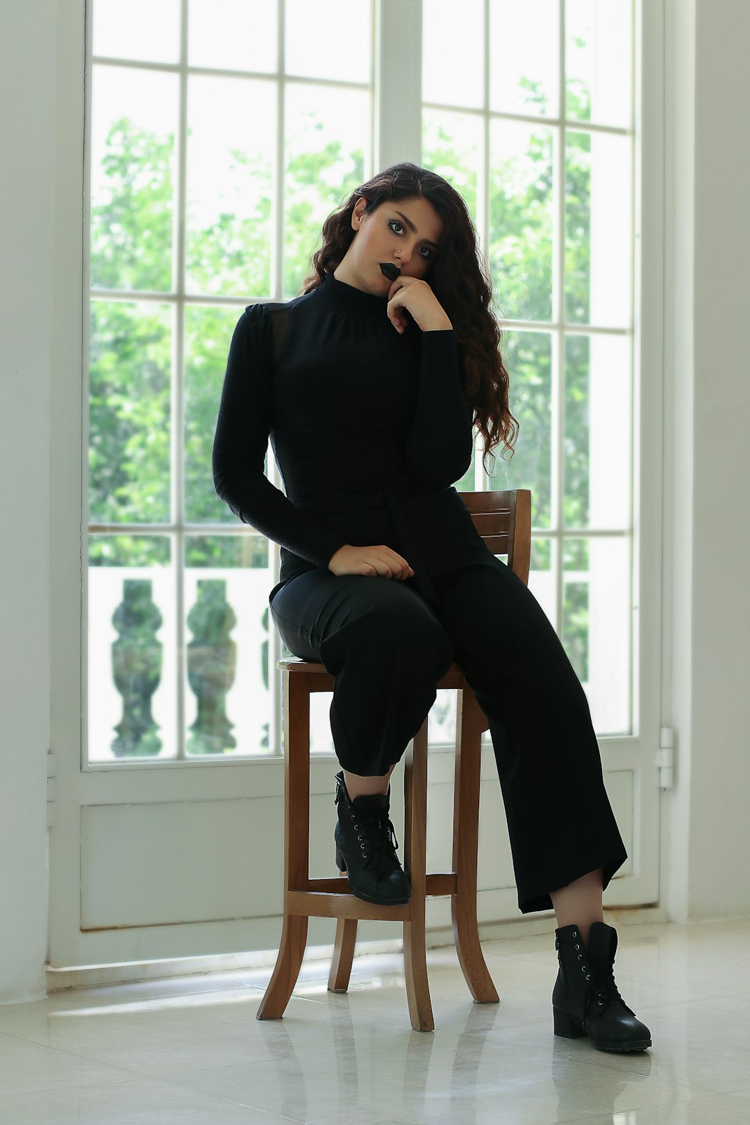 woman in black long sleeve shirt and black pants sitting on brown wooden chair