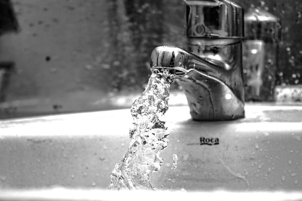water falling from faucet in grayscale photography