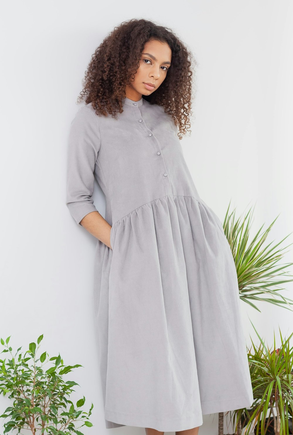 woman in white long sleeve dress standing near green plant