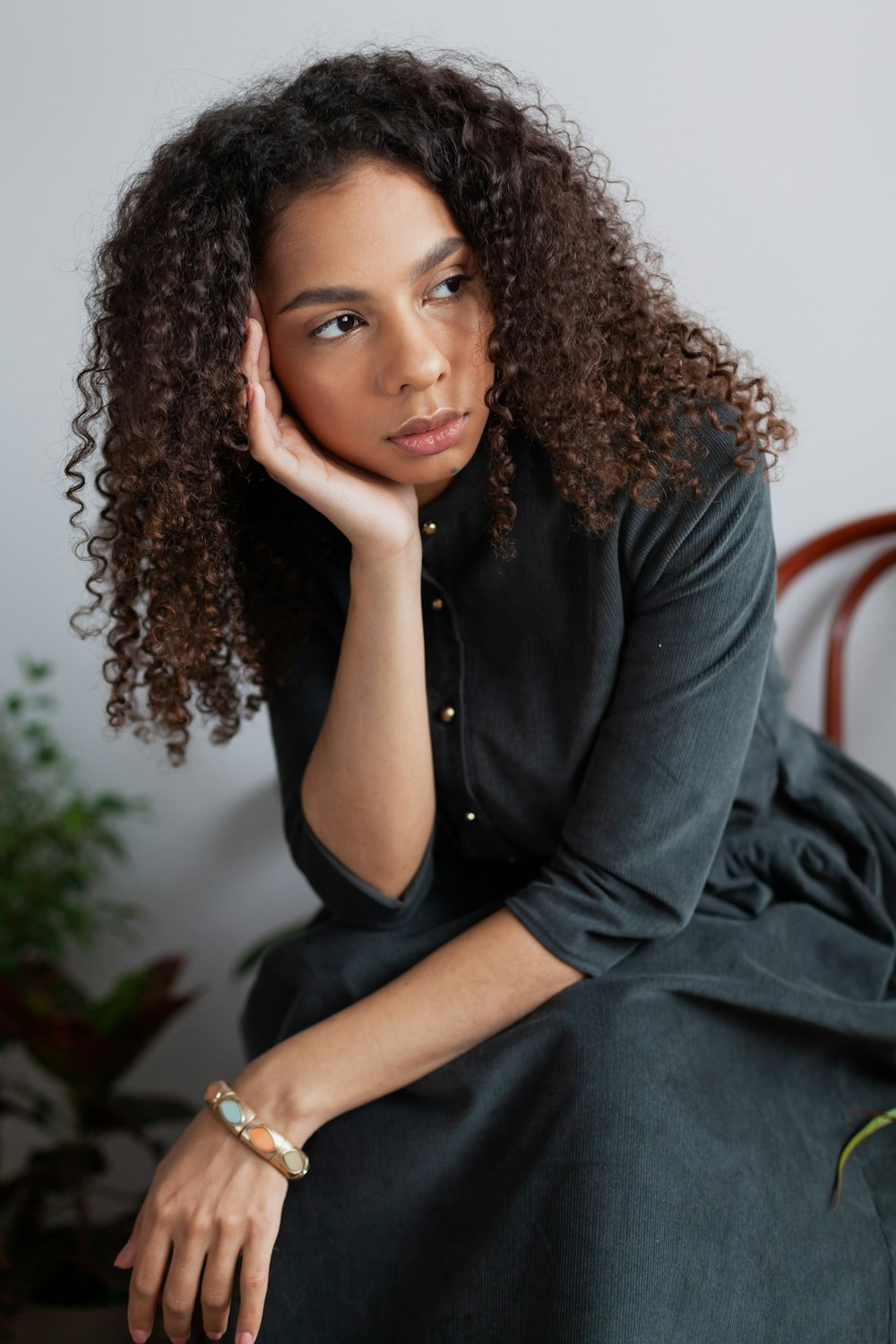 Femme en blazer noir assise sur une chaise en bois marron