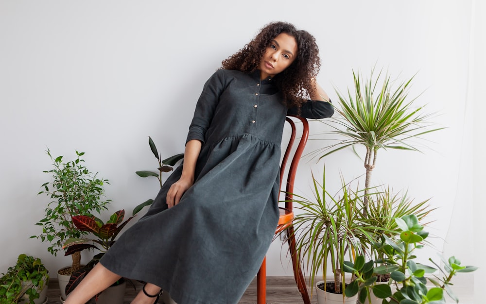 woman in black long sleeve dress sitting on brown wooden chair