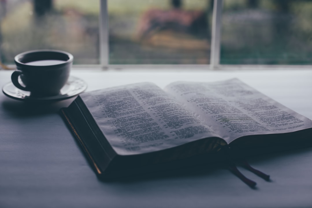 white book page beside black ceramic mug on table