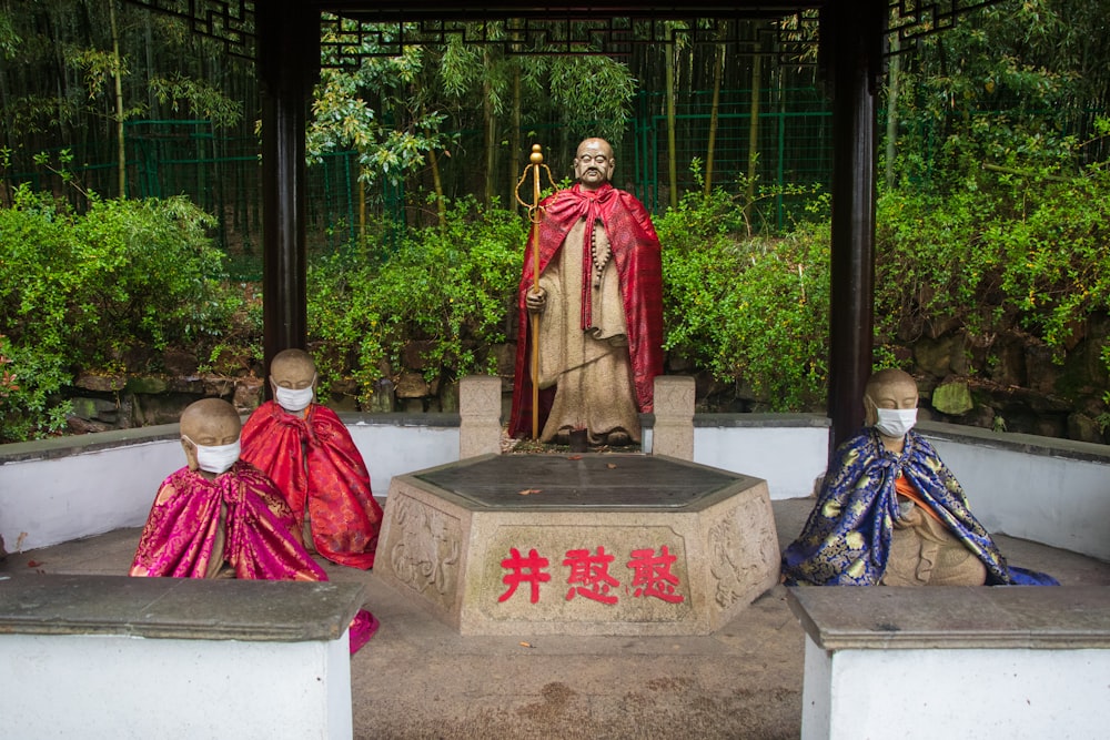 man in red robe sitting on gray concrete bench