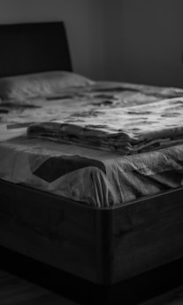grayscale photo of bed with white and black blanket