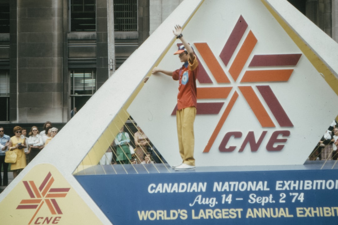 woman in red shirt and brown pants standing on white concrete building during daytime