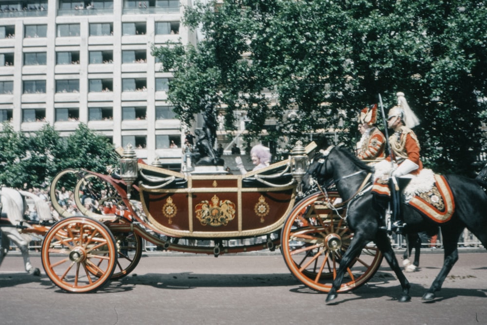 people riding on horse carriage near white concrete building during daytime