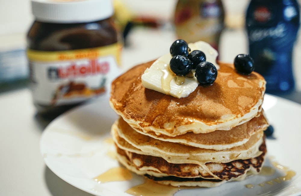 a stack of pancakes topped with blueberries and butter