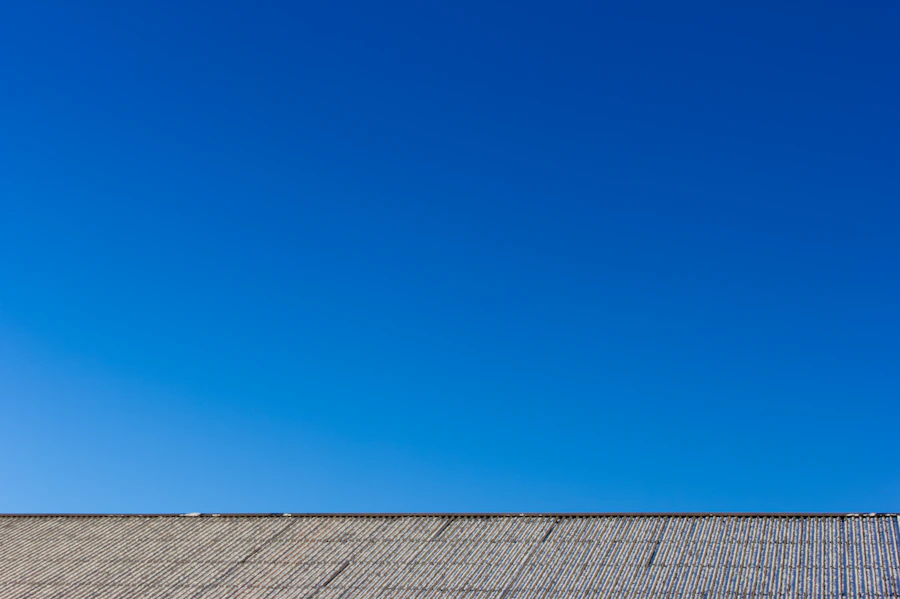 Close-up of a light gray shingle roofline against a blue sky