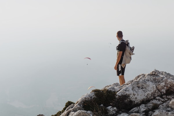 A man at the top of mountain watching three paraglidersby Nicolas Lafargue
