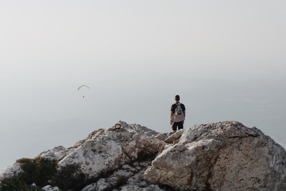 man in black shirt standing on rock during daytime