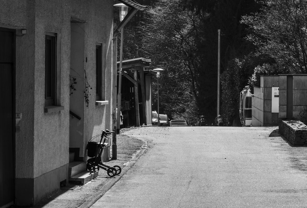 grayscale photo of bicycle parked beside building