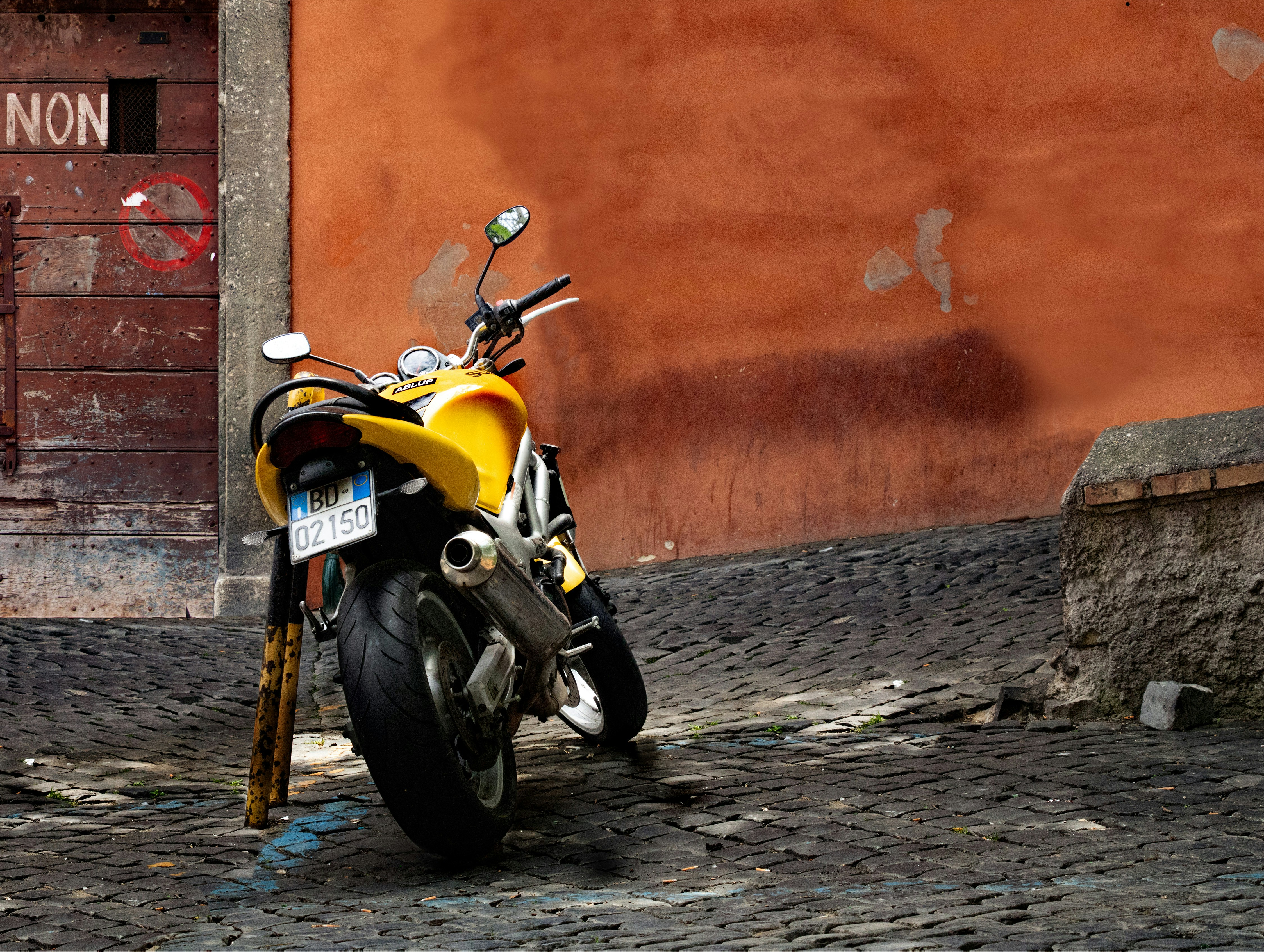yellow and black motorcycle parked beside orange wall