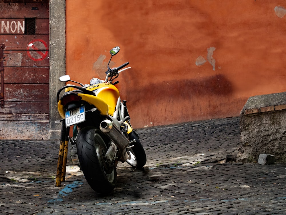 yellow and black motorcycle parked beside orange wall