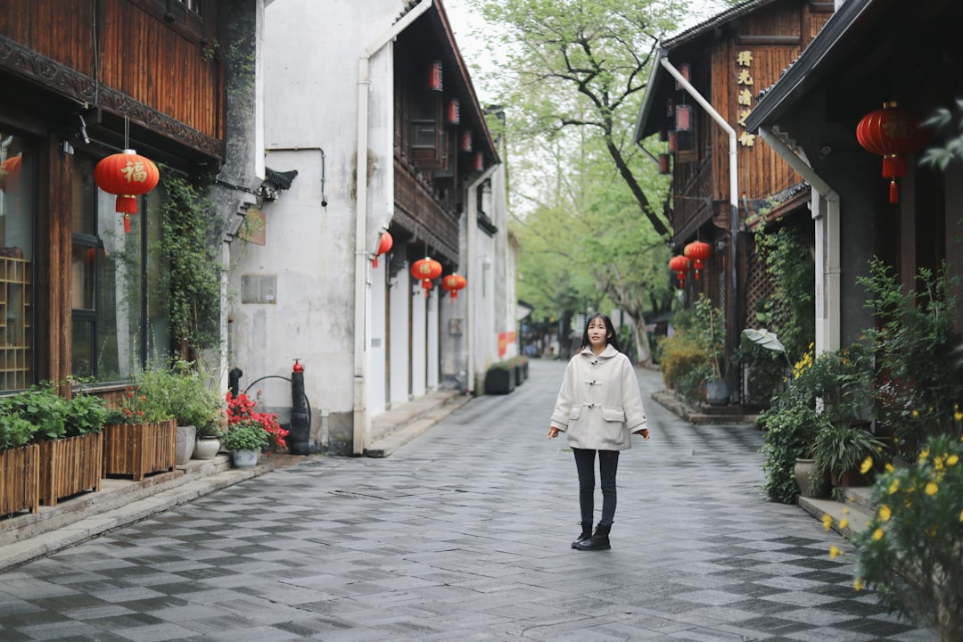 woman in white coat walking on sidewalk during daytime