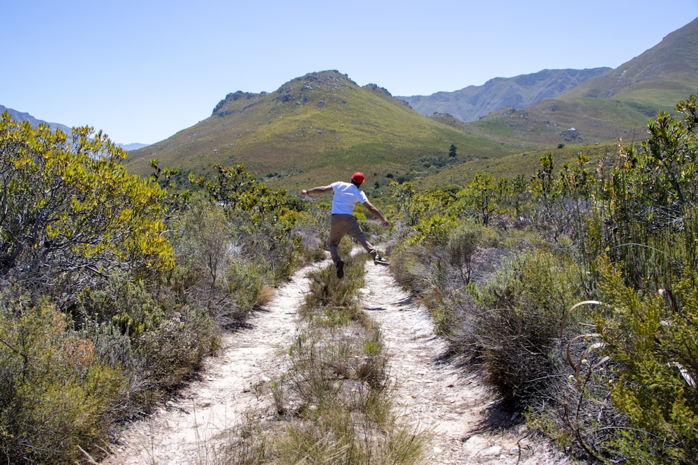 a man riding a skateboard down a dirt road