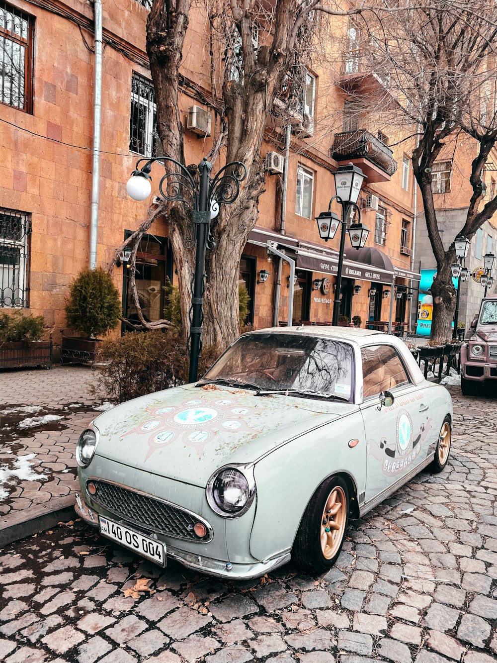 white classic car parked beside brown concrete building during daytime