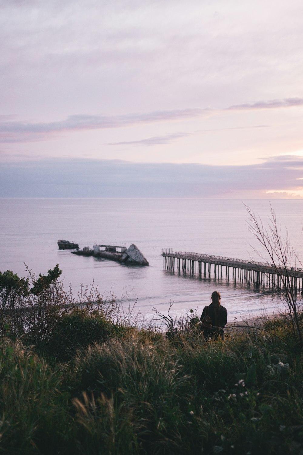 person sitting on rock near body of water during daytime