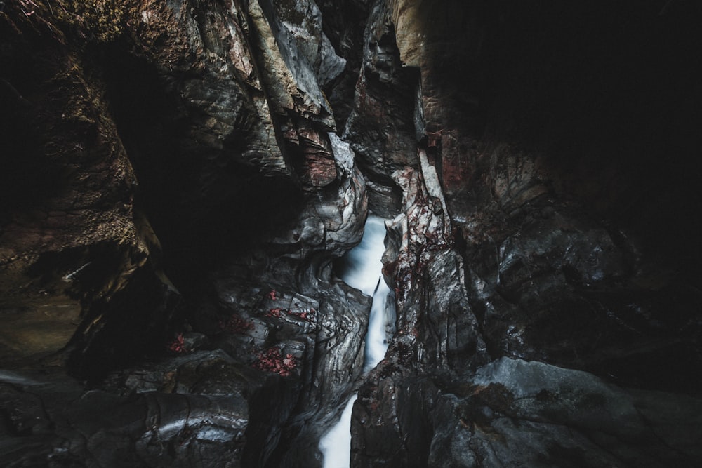 water falls between brown rocky mountain during daytime