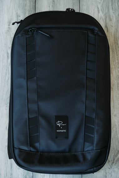 A sleek, navy blue backpack with subtle branding, resting on a polished wooden desk.
