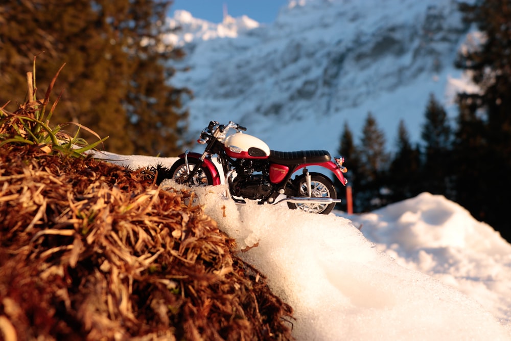 a red and white motorcycle parked on top of a pile of snow