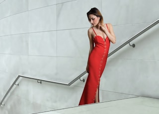 woman in red sleeveless dress standing beside white wall
