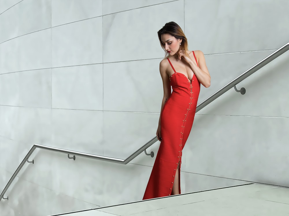 woman in red sleeveless dress standing beside white wall