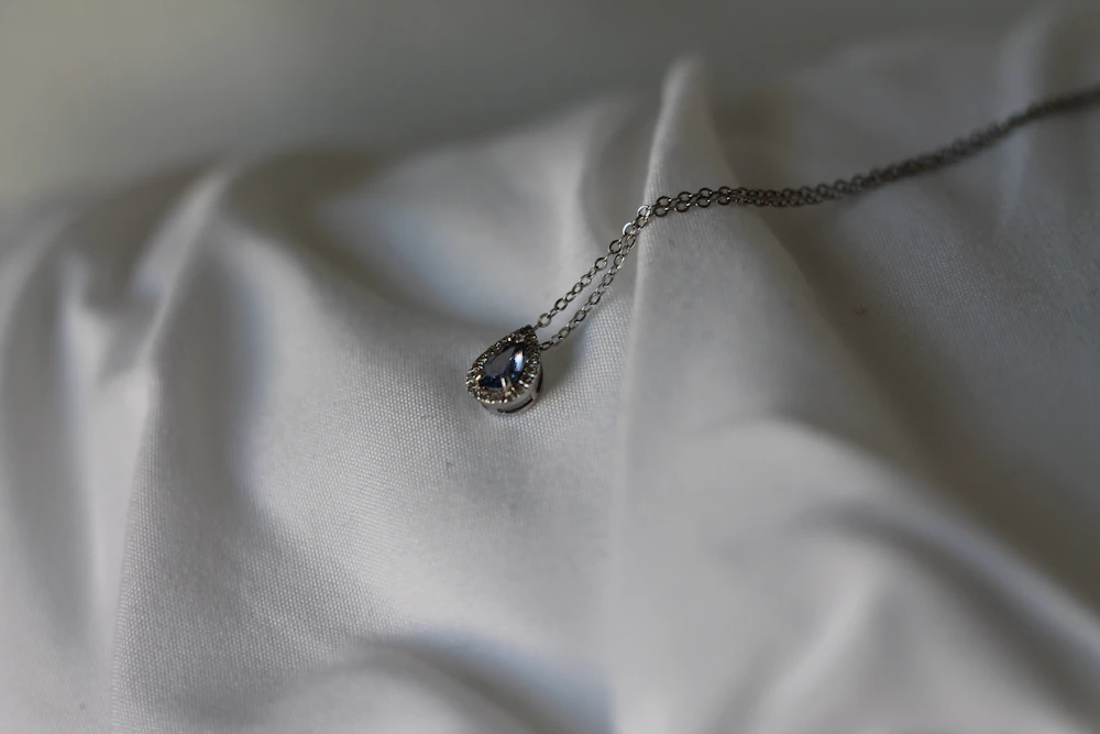 Silver necklace with a small gemstone pendant on silk fabric