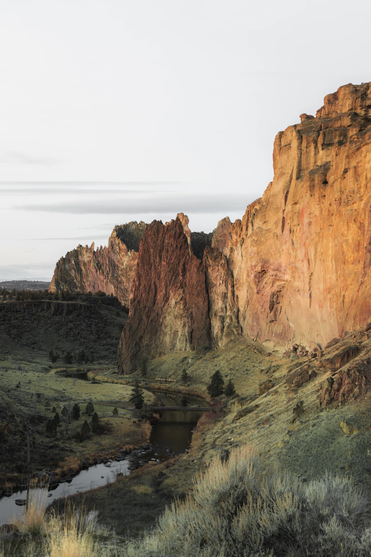 Brown rock formation beside water — the kind of canyon walls that hold Lake Billy Chinook
