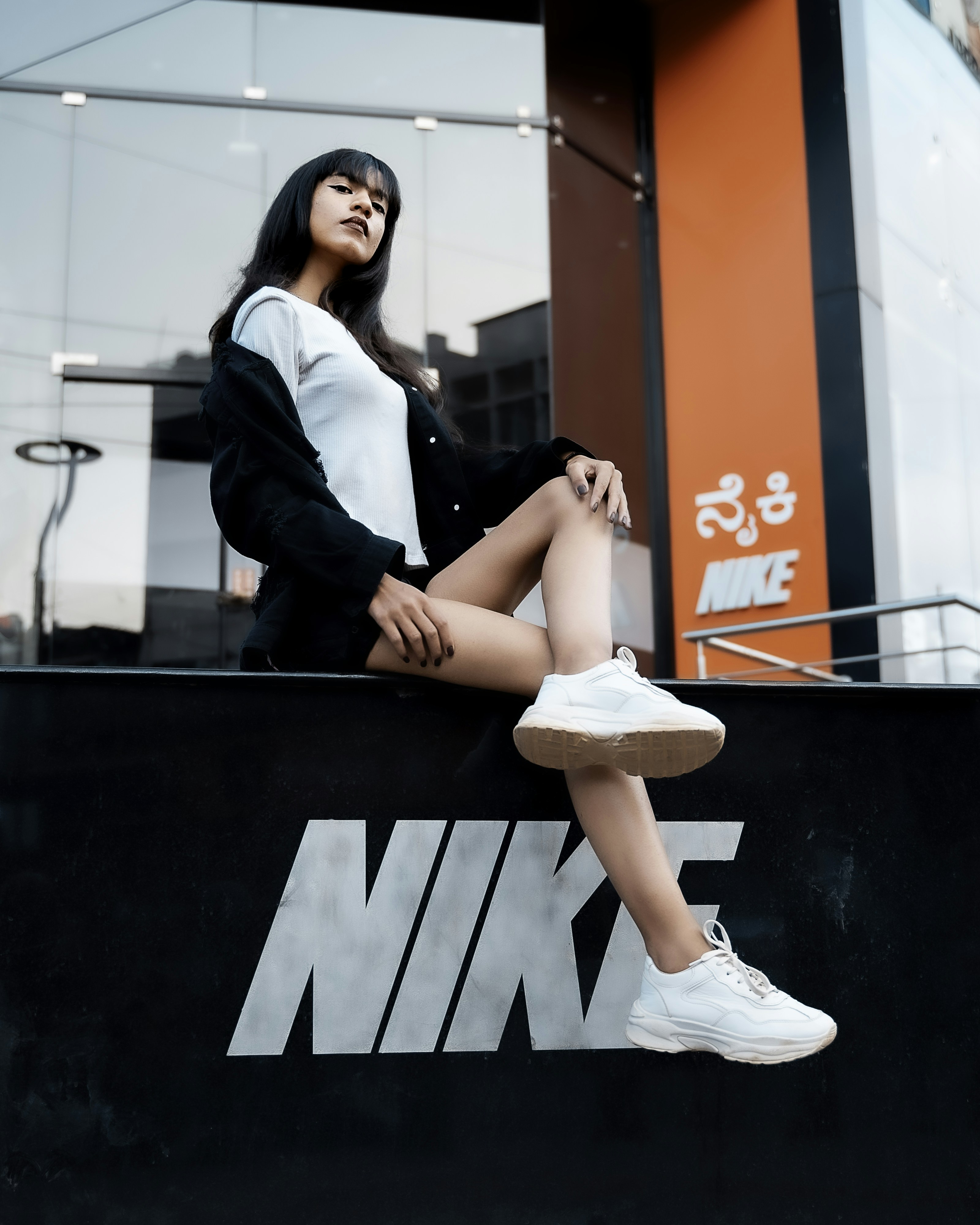 Wanita dengan blazer hitam dan celana putih duduk di atas meja hitam
