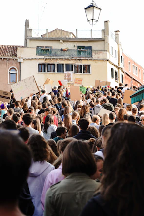 A peaceful protest with diverse crowds holding colorful banners in a European square.