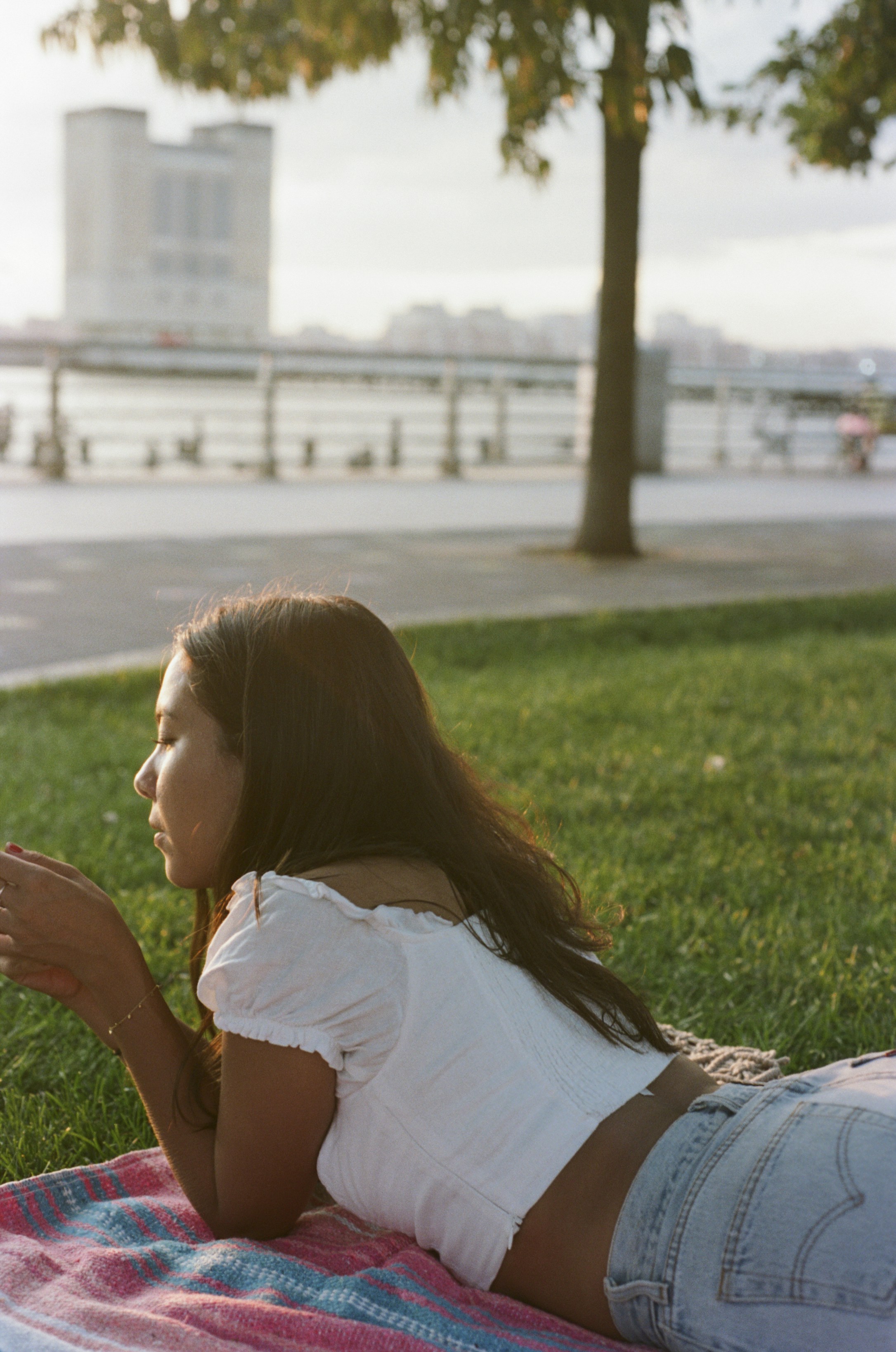 girl in white shirt sitting on green grass field during daytime