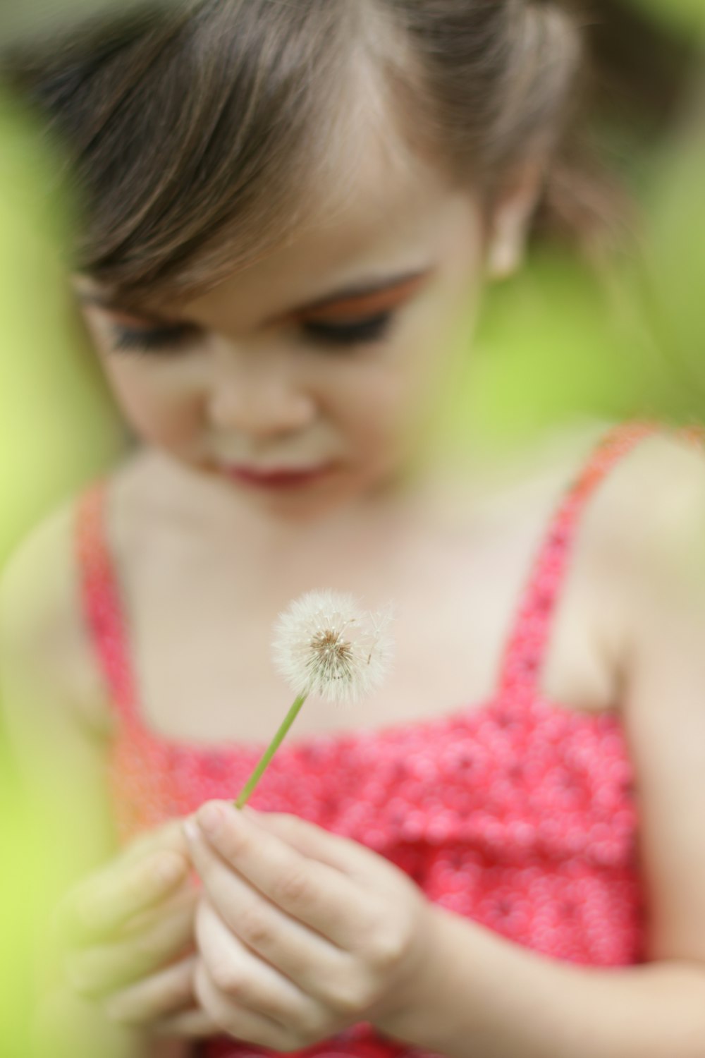 girl in pink tank top holding white dandelion flower