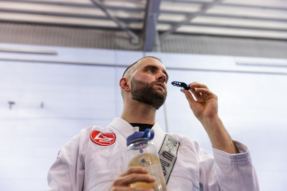 man in white button up shirt holding black smartphone