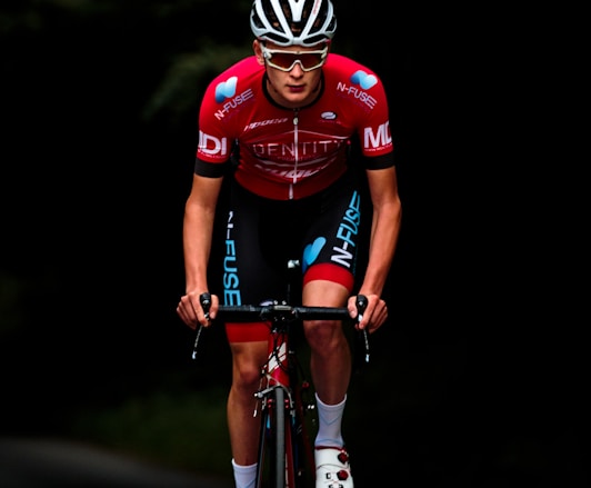 man in red and black bicycle suit riding on black and red bicycle